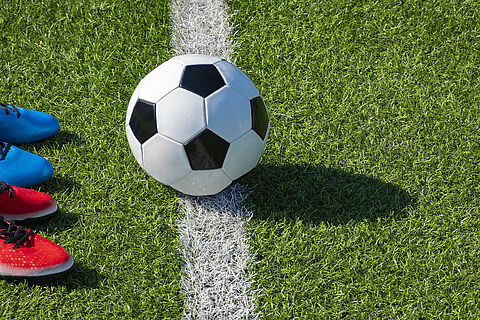 Soccer football background. Soccer ball and two pair of football sports shoes on artificial turf soccer field